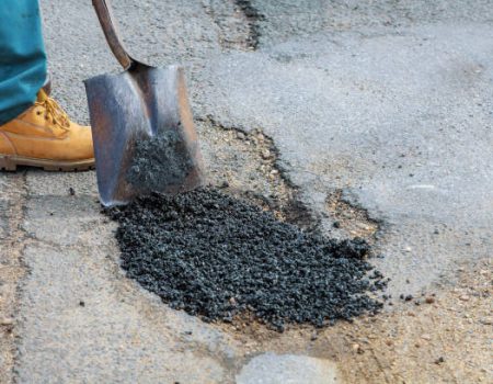 Laying new asphalt, covering the pit, hole in asphalt with very bad quality road